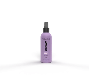 Purple spray bottle labeled FLOWY Vitality standing on a purple surface, with a gray rectangular device in the background.
