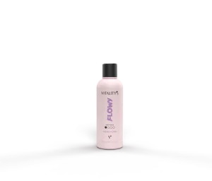 Pink bottle labeled 'Flowy' on a glossy reflective surface with a pale pink background behind it.
