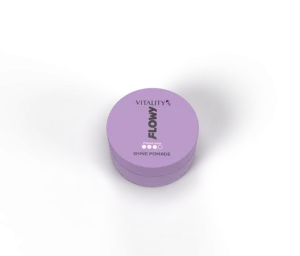 Purple circular jar of Vitality's Flow Shine Pomade viewed from above, resting on a dark surface with hair framing the scene.