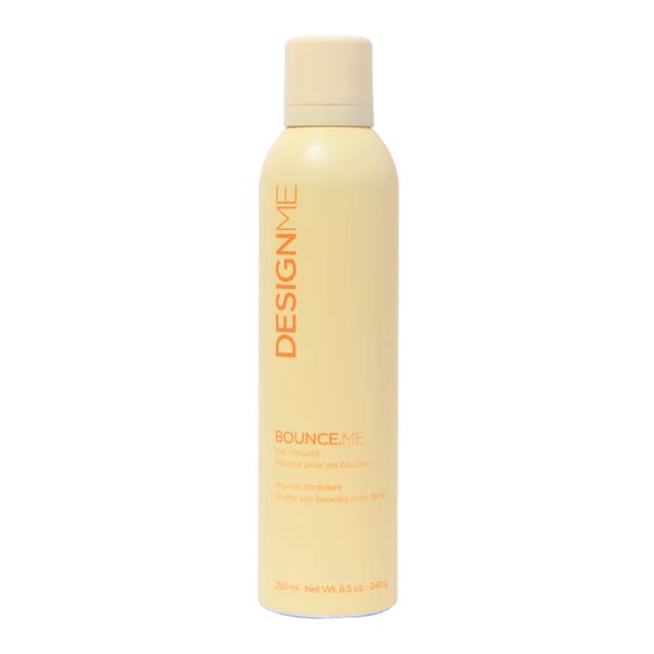 Tall pale yellow bottle of Design.ME Bounce.Me hair product with orange vertical logo text down the side.